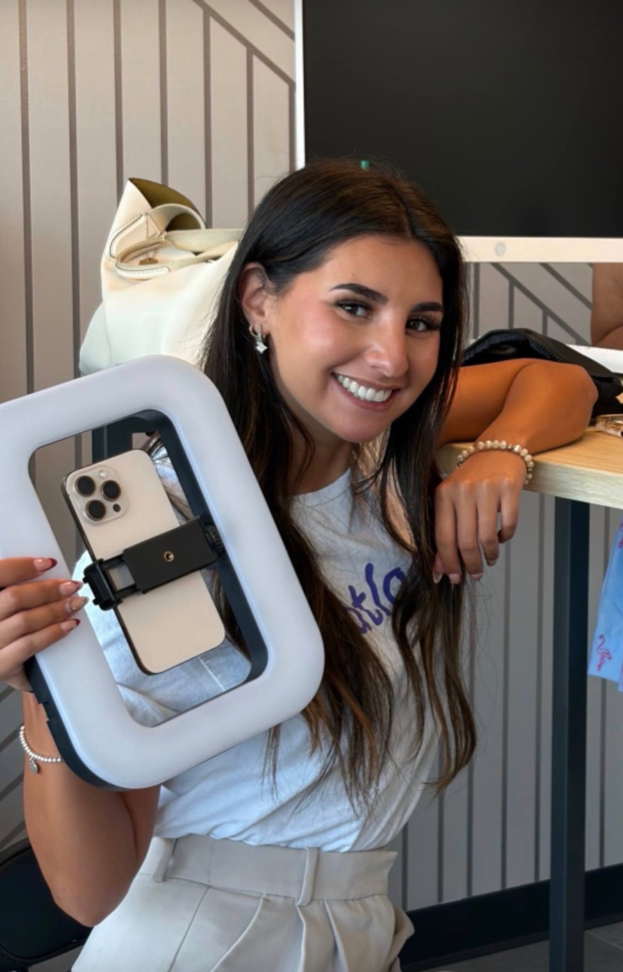 An atLocal content creator smiling and holding a phone in a ring light