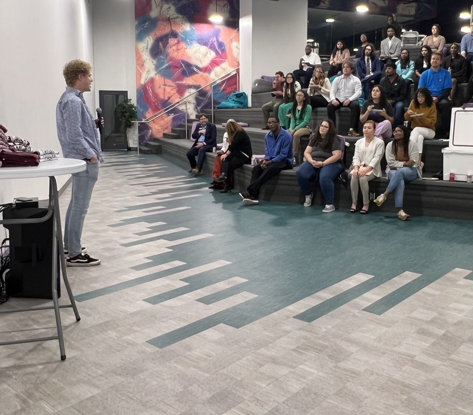 An atLocal presenter with a microphone speaking to a seated audience of business owners and staff